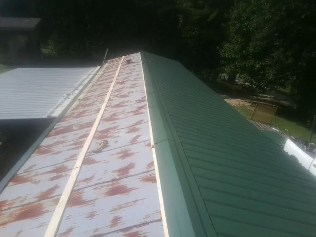 Old rusted panels beside newly installed green metal roofing — Wind Damage Roof Repair by Roofing Brothers in Lees Summit