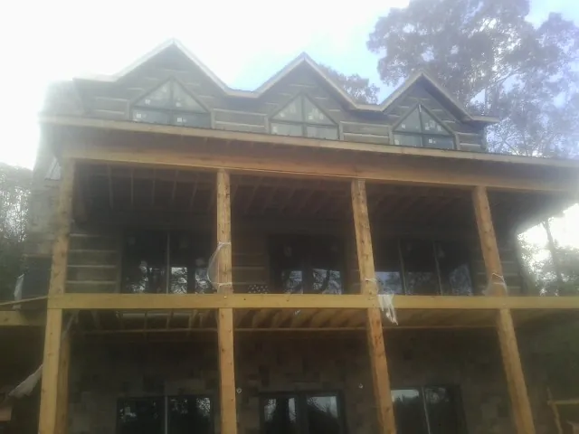 Dormers and porch framing on a large log home under construction — Roof Coating work by our crew in Lees Summit
