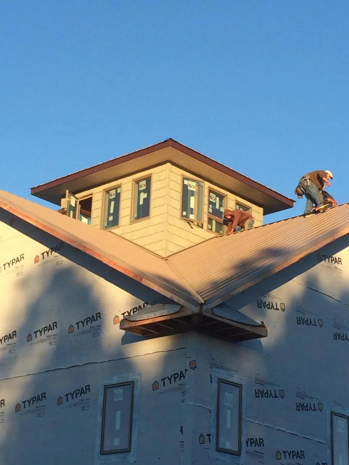 Roofers working around a rooftop cupola on a new metal roof at sunset — Roof Waterproofing in Lees Summit by Roofing Brothers